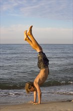 Youth doing a handstand at the Baltic Sea beach