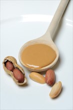 Peanut puree in cooking spoon and peanuts