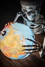 Skeleton with bony hand on globe