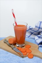 Carrot juice in glass and carrot slices on wooden board