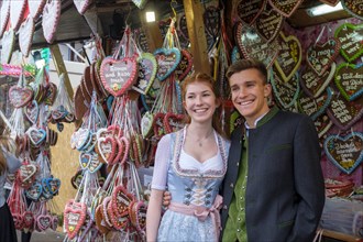 Young couple in traditional traditional traditional traditional traditional traditional traditional traditional traditional traditional costume in front of gingerbread hearts
