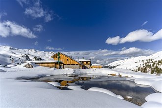 Snowy Lizumer Hut with small mountain lake in winter