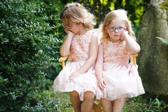 Portrait of two sisters sitting together on a garden chair (6 years old