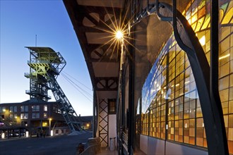 Illuminated machine hall with winding tower in the evening