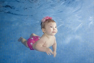 Little baby learning to swim underwater in a swimming pool