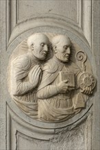 Relief of two priests at the entrance of a church