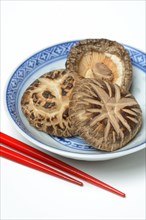 Dried shiitake mushrooms in bowls and red chopsticks