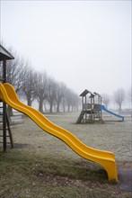 Children's slide in autumn fog on a playground