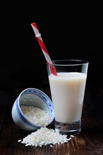 Rice milk in glass with drinking straw and rice grains