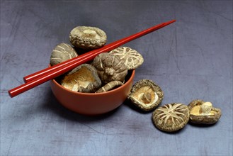 Dried shiitake mushrooms in bowl and red chopsticks