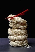 Stacked Asian nest noodles and red chopsticks