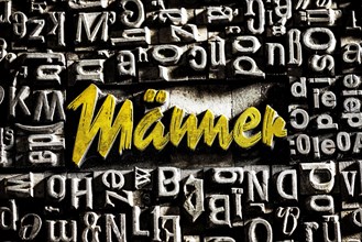 Old lead letters with golden writing show the word Maenner