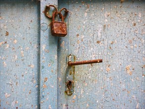 Old door lock with door handle on weathered wooden door