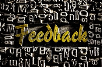 Old lead letters with golden writing show the word Feedback
