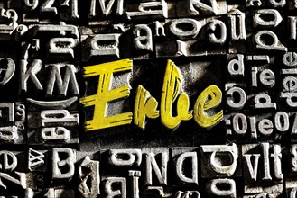 Old lead letters with golden writing show the word Erbe