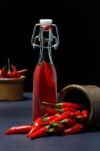Chili oil in bottle and red chillies with ceramic vessel