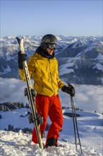 Skier stands at the ski slope and holds ski