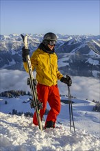Skier stands at the ski slope and holds ski