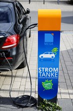 Electric car fills up on green electricity at a power charging station