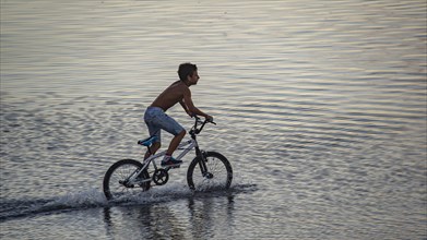 Boy rides his bike on a flooded terrace