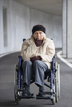 Thoughtful senior citizen in wheelchair in an underpass