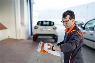 Delivery man with a small orange parcel looking on the watch