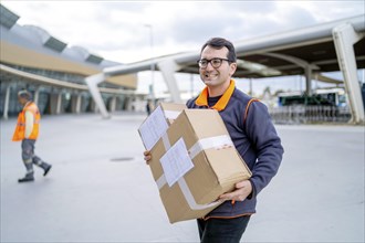 Happy courier with a parcel delivering to a business area