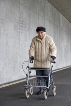Senior citizen with walker walks in an underpass