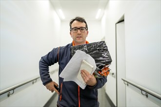 Courier with the package and documents in his hand in white corridor