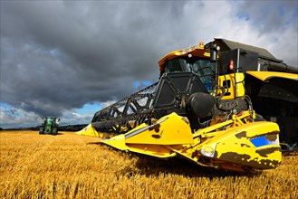 Combine harvester and tractor during the harvest in a cornfield
