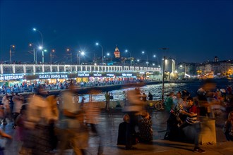 People in front of the Galata Bridge at night