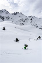 Ski tourers on the descent in deep snow