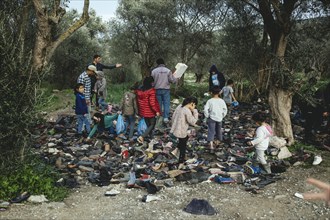 Refugees look for shoes from a pile of donations