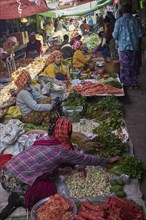 Market woman offer vegetables and sit on the floor