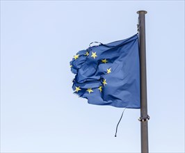 Torn European flag fluttering in the wind at the flagpole