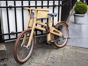 Wooden bicycle chained to an iron fence