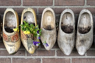 Old clogs with flower decoration on a house facade