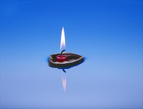 Burning candle in nutshell floats on water