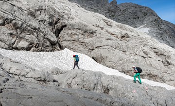 Female mountaineers on marked route through rocky alpine terrain