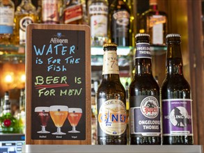 Different beer bottles and funny sign in a bar