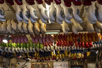 Traditionally colourfully painted Dutch clogs hanging from the ceiling in a clogs workshop