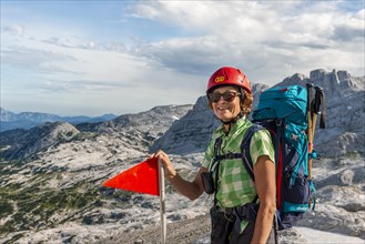 Mountaineer with backpack and helmet looks happily into the camera