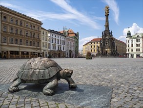 Sculpture of a turtle on the Oberring square with Unesco World Heritage Column of the Trinity