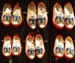 Colourfully painted traditional Dutch wooden shoes hanging on a wooden wall
