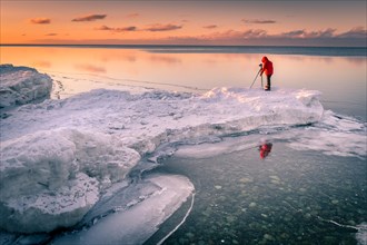 Tourist taking pictures on the shore of the partly frozen Lake Khuvsgul in winter