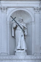 Sculpture of a saint with cross in a wall niche