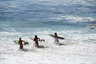 Three tourists with surfboards at Jimbaran Beach