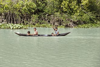 Native woman with small children rowing in a dugout boat in the Orinoco Delta