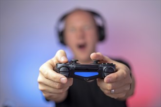 Gamer with headphones and gamepad having a lot of fun