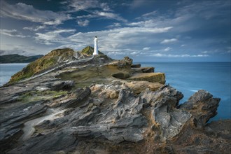 Lighthouse in the evening light on the cliffs of lava rock at Castlepoint, Masterton
